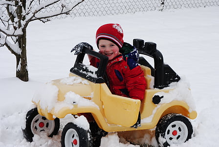 boy riding a yellow vehicle ride-on toy outside with snow