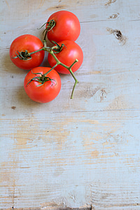 four tomatoes on beige wooden table