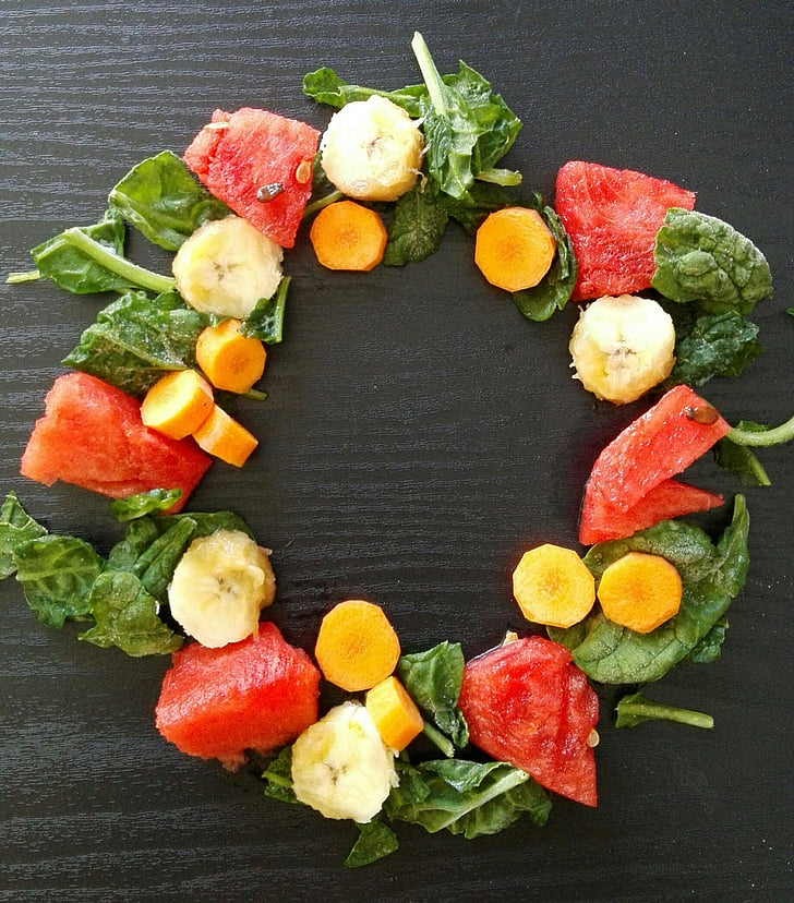 circle formed sliced watermelon, banana, and carrots with green spinach