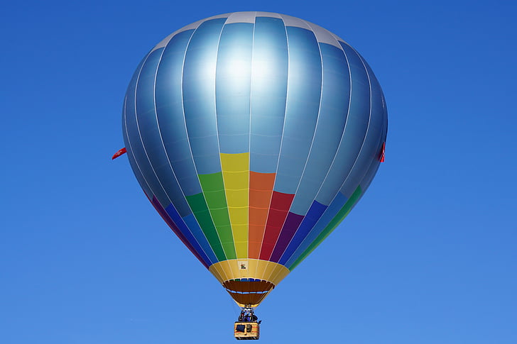 blue, yellow, and orange hot air balloon in flight at daytime