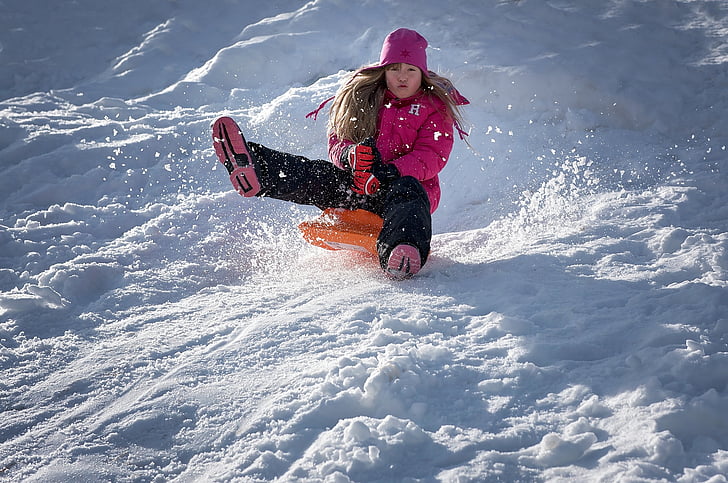 Royalty-Free photo: Woman riding on orange board sliding on snow filled  mountain