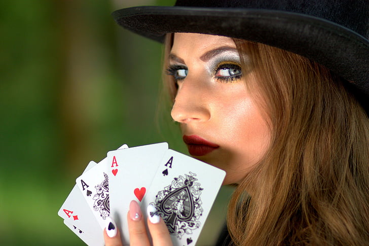 woman wearing black hat holding ace playing cards