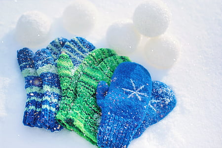 three pairs of blue and green snow gloves on snow