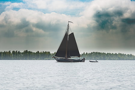boat sailing on body of water under cloudy daytime