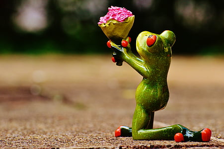 green frog giving flowers while kneeling down figurine