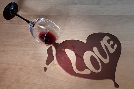 black and clear wine glass showing heart-shaped liquid with love text