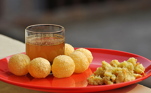 shallow depth of field photo of round fried food on red plate beside rocks glass