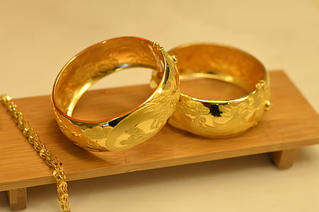 two gold-colored rings on brown wooden platform