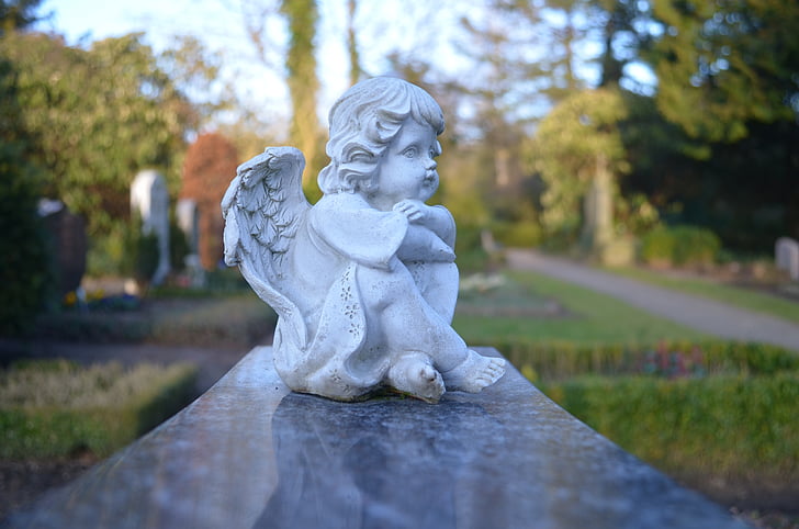 tilt-shift lens photography of sitting white cherub figurine