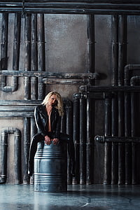 woman wearing black leather jacket seating on a silver drum
