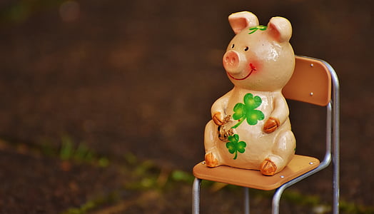 orange, green, and brown ceramic pig figurine on brown chair