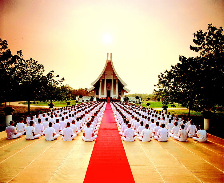 people sits on ground front of temple at sunset