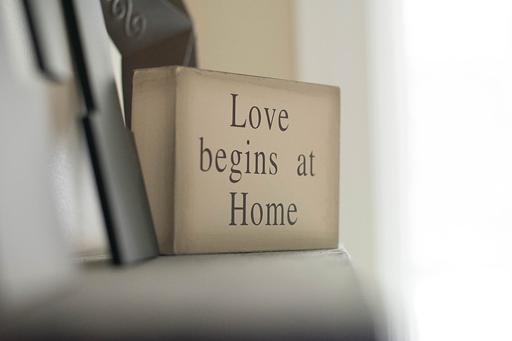 selective focus photography of love begins at home decorative wood block on white shelf
