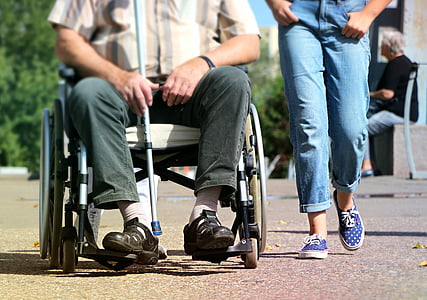 man siting on wheelchair beside person in jeans
