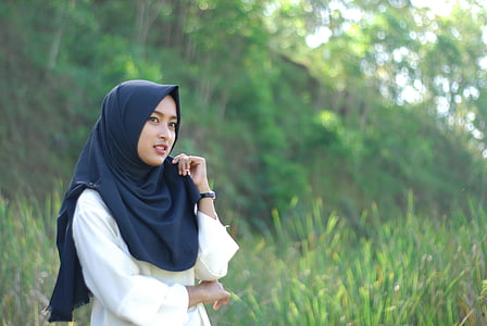 woman wears black hijab surrounded by green grass during daytime