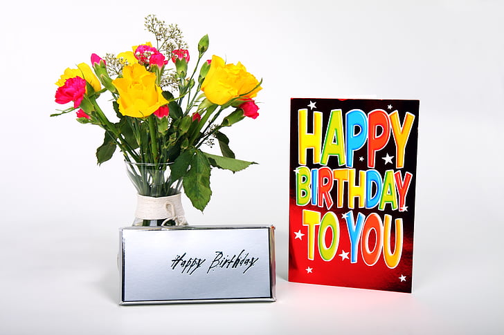yellow, green, and red flower arrangement beside birthday greeting card