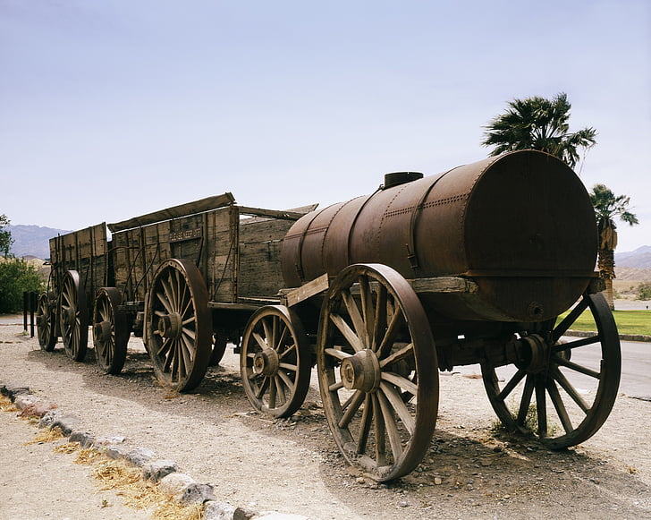 brown wooden carriage on roadway with barrel