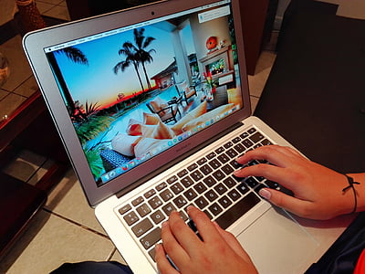 person using MacBook Air displays pool and tree wallpaper