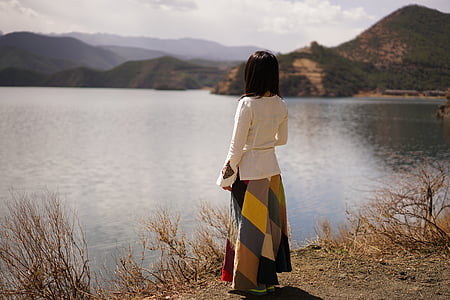 woman in white long-sleeved standing near body of water during daytime