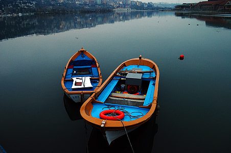 two blue-and-brown rowboats on body of water