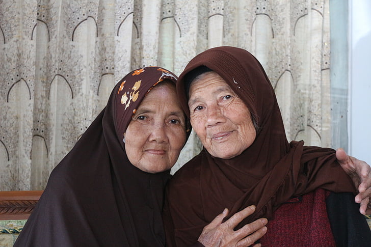 two woman sitting wearing hijabs