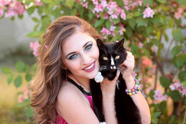 woman wearing pink top holding black cat