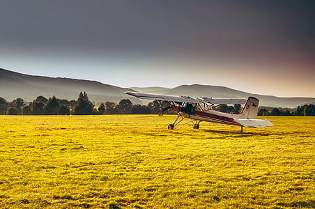 white and red plane on top of green grass lawn during dawn