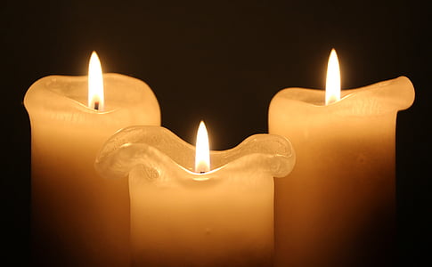 three white lighted pillar candles
