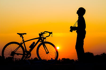 silhouette of man standing near road bike
