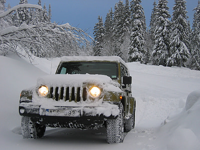 green Jeep Wrangler on snowfield near trees