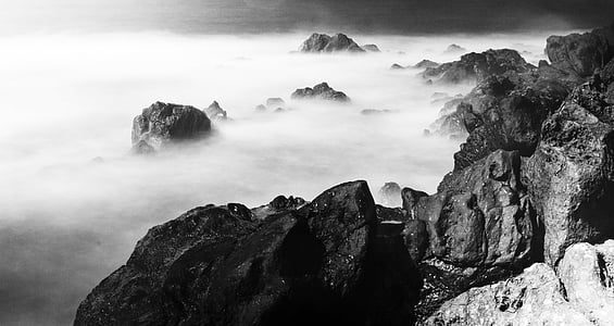grayscale photo of mountain cliff and sea of clouds