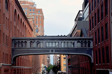empty bridge connecting two red concrete buildings during daytime