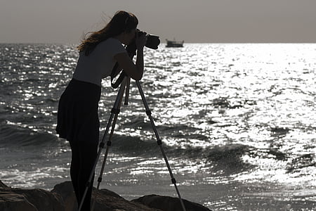 woman taking a photo on rock formation through the ocean