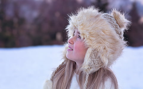 woman in beige Russian cap looking up on snow covered ground