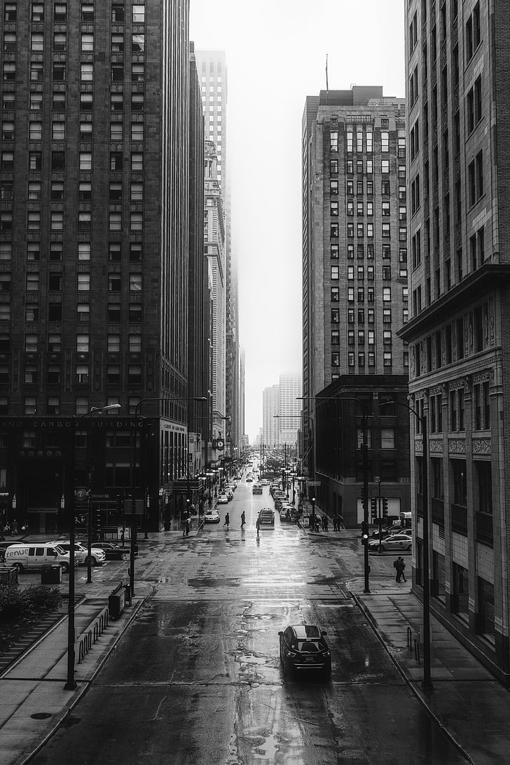 greyscale photo of city road and tall buildings