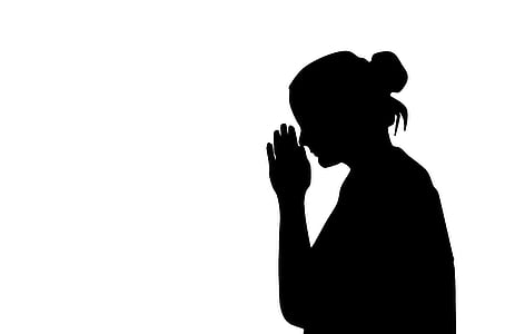 silhouette of woman with her hands together in front of her face