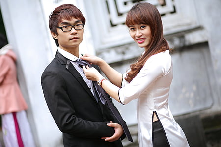 woman holding fixing man's necktie