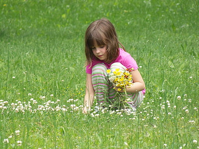 photo of girl picking up flowers in field