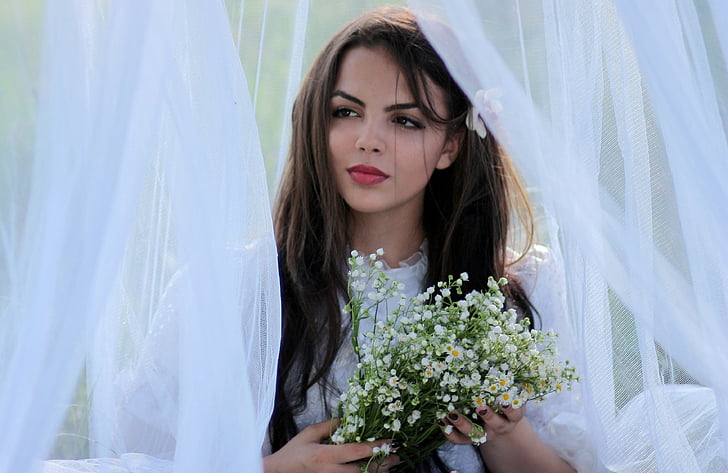 woman in white puff-sleeved top holding bouquet of baby's breath flowers