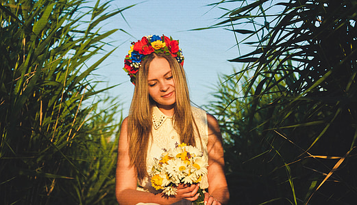 woman holding bouquet of flowers standing in between grass during daytime