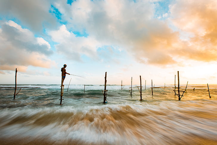 time lapse photo of kid fishing on seashore during daytime
