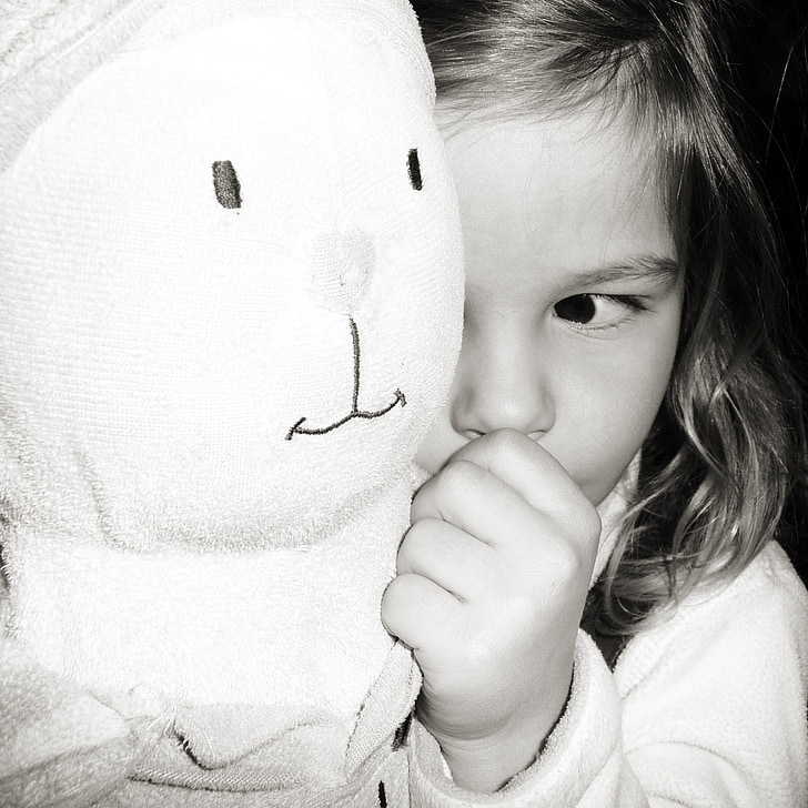 grayscale photography of a child holding her plush toy