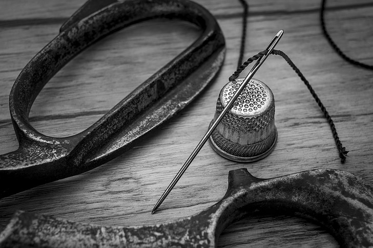 scissors, sewing needle, and thimble grayscale photo