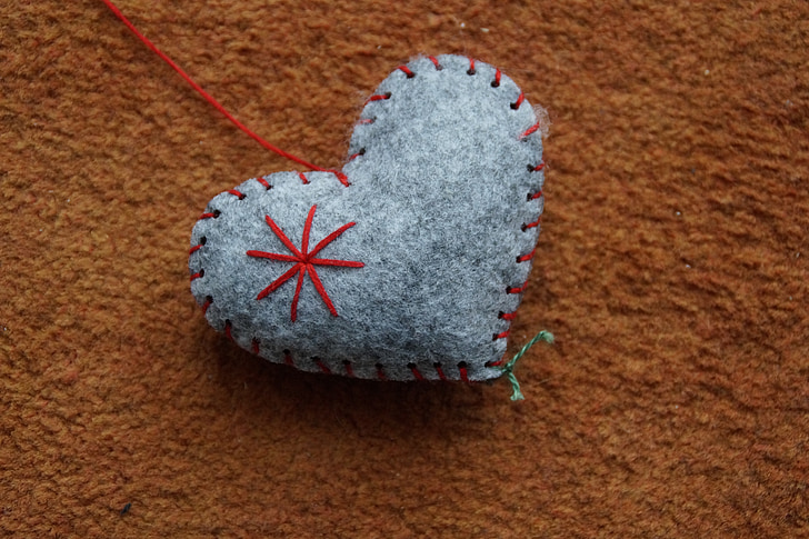 gray heart-themed pincushion on brown textile