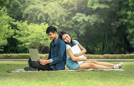 couples sitting on green brown textile on green grass field