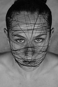 grayscale photo of woman's face covered with black thread