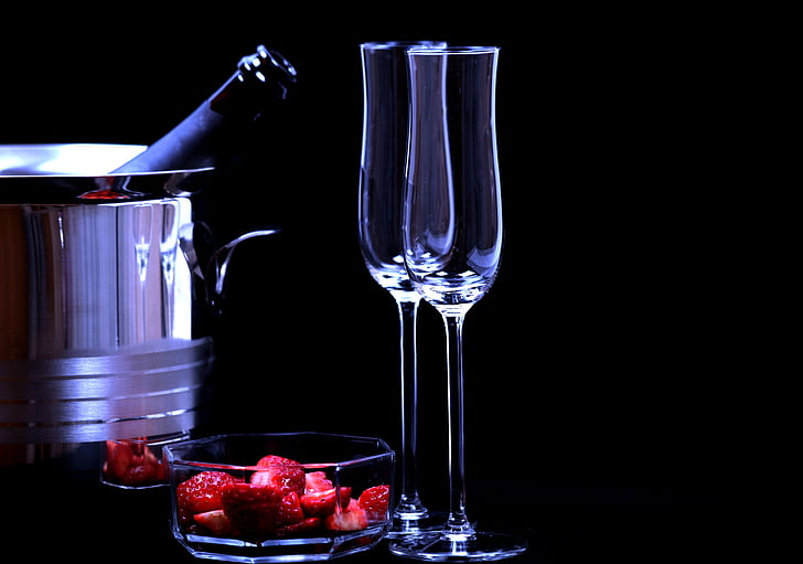 two empty clear wine glasses beside clear glass bowl with strawberry fruits