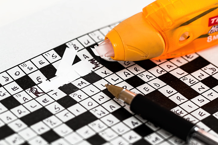 black and white crossword puzzle with pen and correction tape