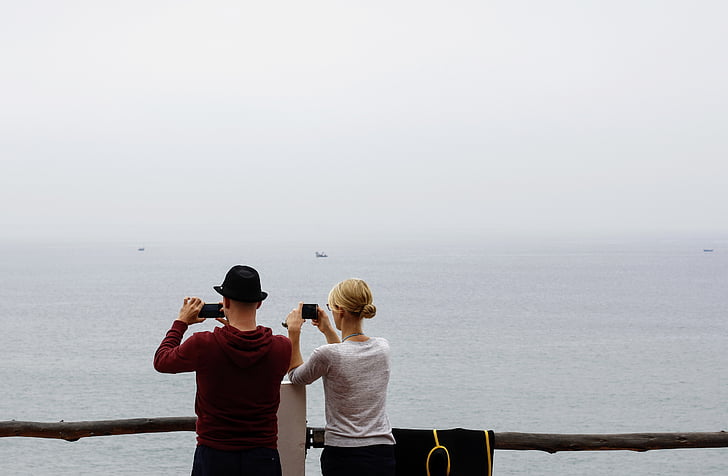 man and woman taking photo at the sea