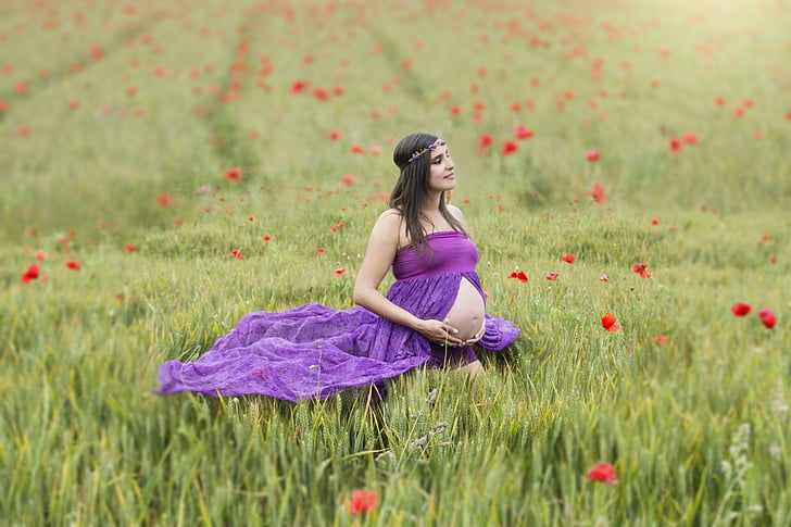 pregnant woman in purple dress in the middle of grass field